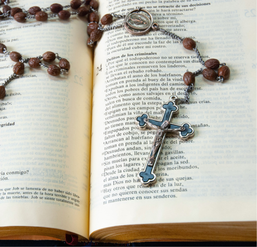 Rosary laying on an opened Bible. 